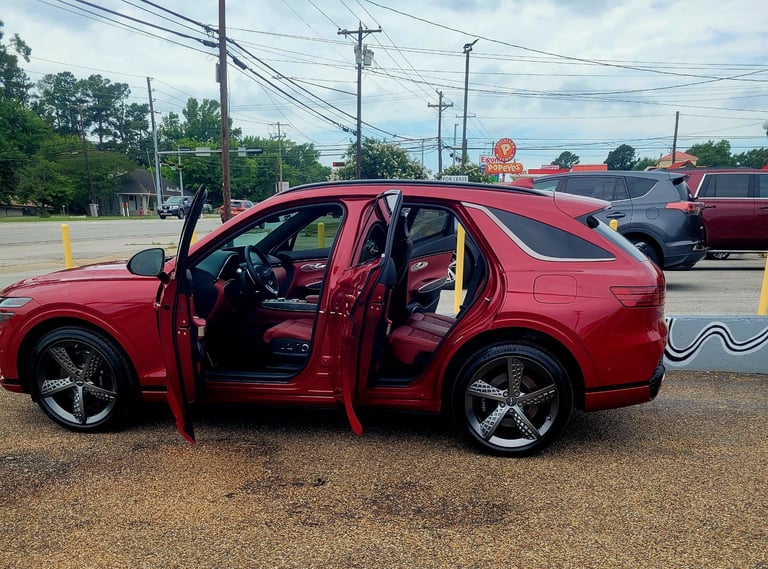 Red SUV with open doors parked in a lot, surrounded by power lines and trees in daylight