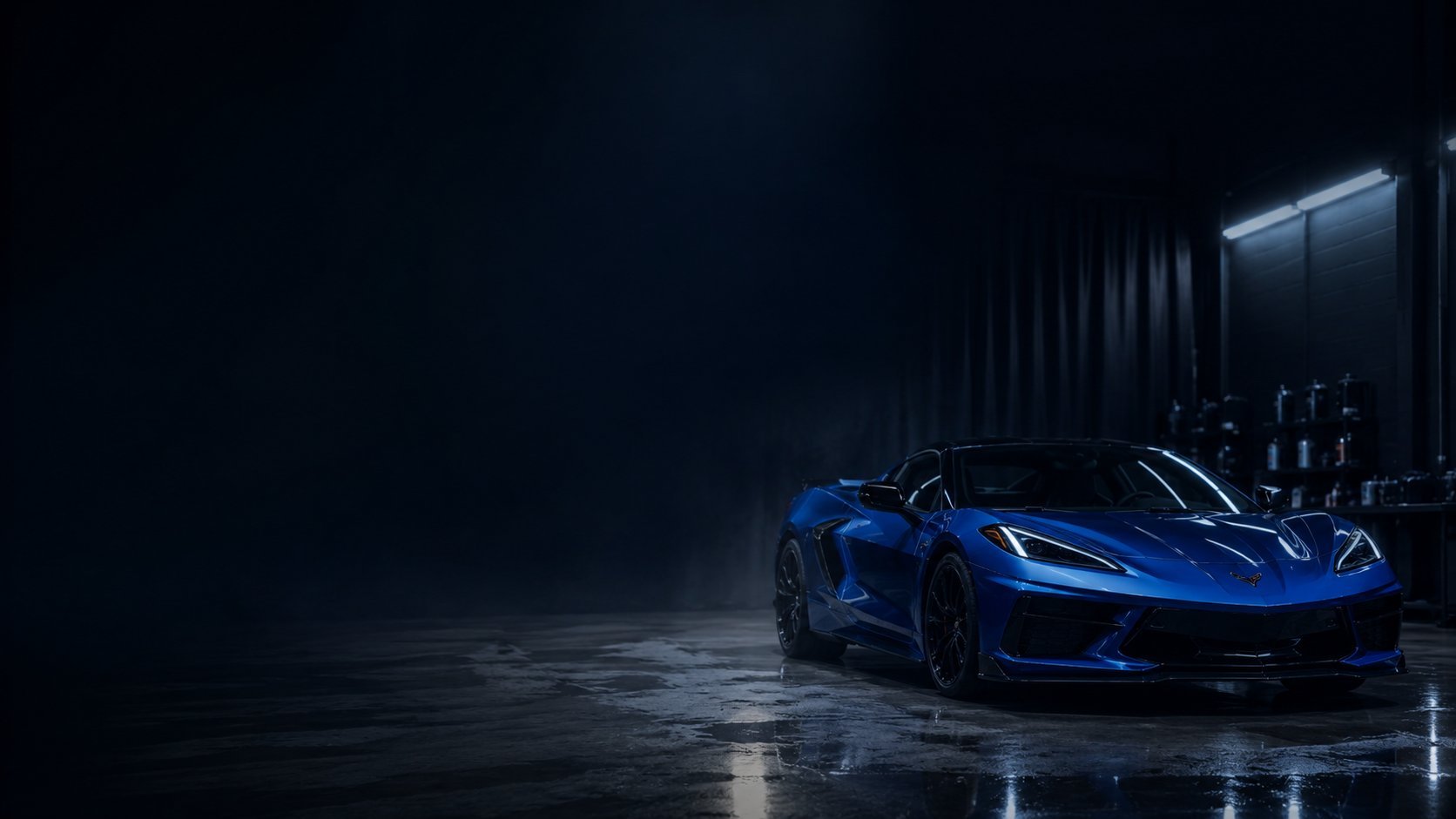 Blue sports car parked in a dark industrial garage with wet concrete floor and moody lighting