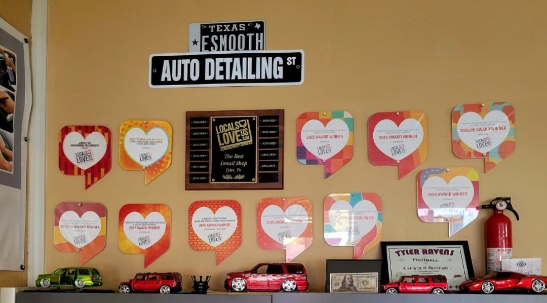 Display shelf with Texas Smooth Auto Detailing sign, heart-shaped customer testimonials, toy cars, and red fire extinguisher