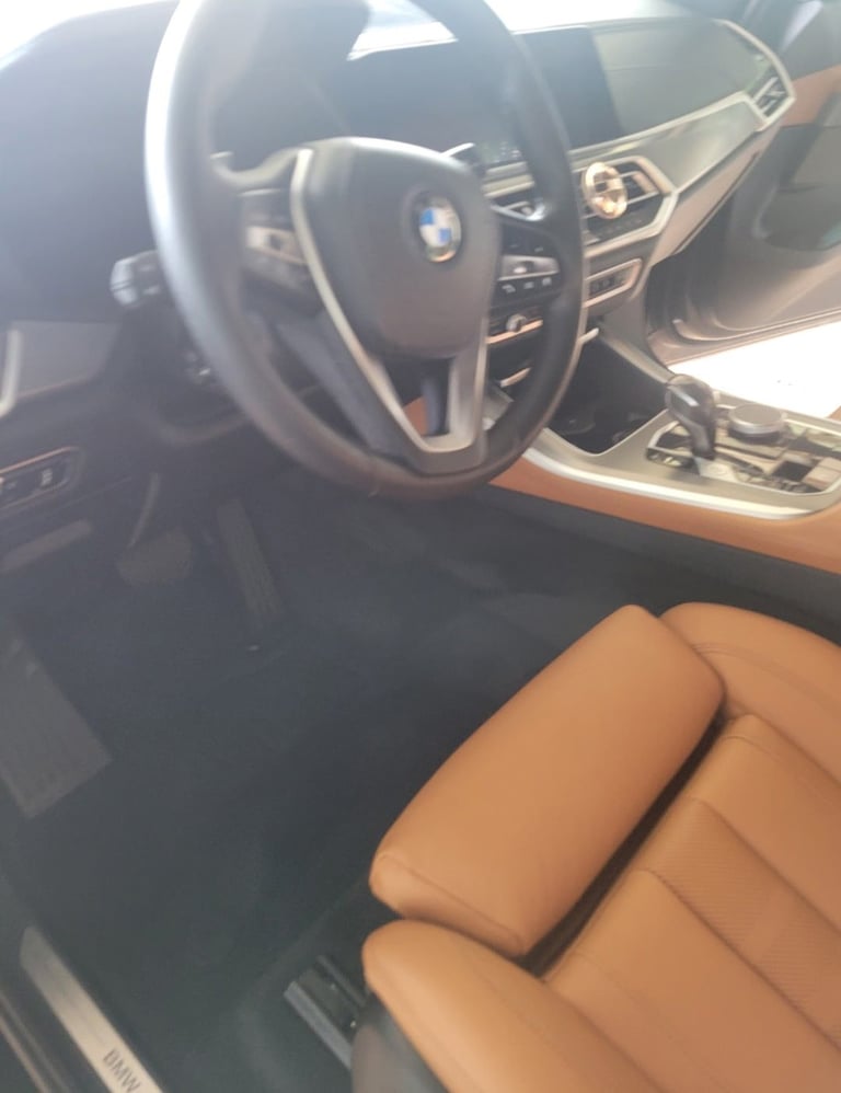 Interior of a luxury car showing steering wheel, dashboard, and tan leather seats