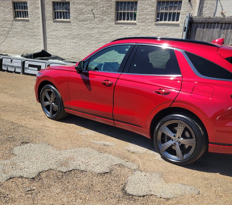 Red SUV parked on gravel lot with stone building and windows in background